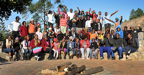 A large group of happy people standing in front of the firepit at Ekukhanyeni