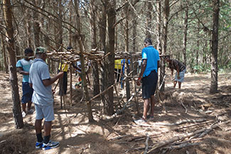 Kids working together and building a hut out of sticks at Ekukhanyeni