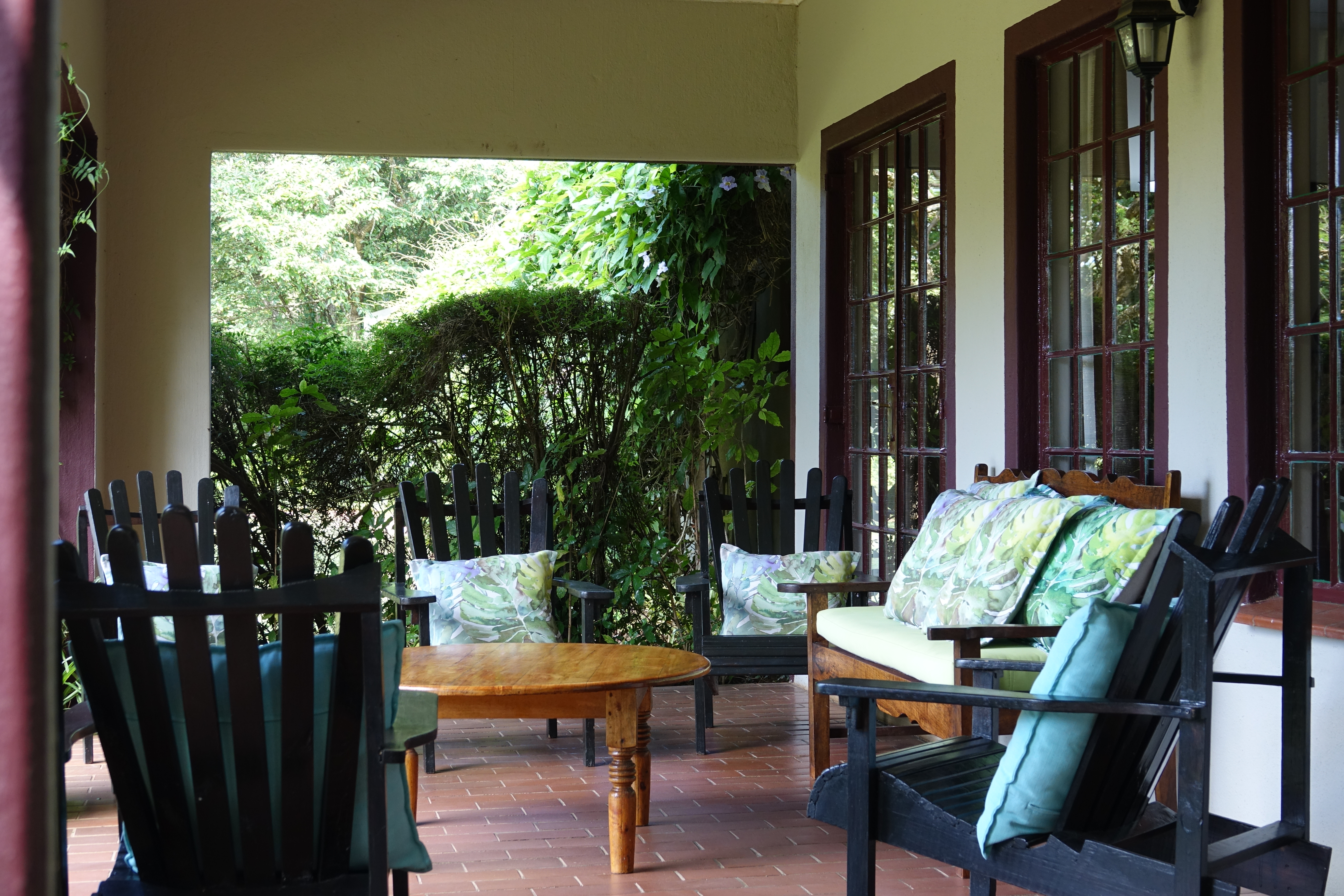 An outside look of the peaceful porch at Ekukhanyeni, with 4 chairs surrounding a table